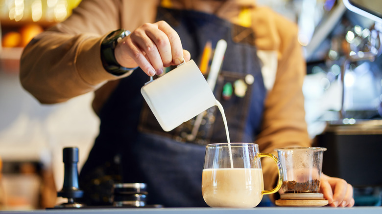 barista pouring cream in tea