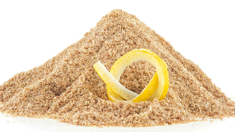 A loop of fresh lemon peel sitting in a pile of dried peel