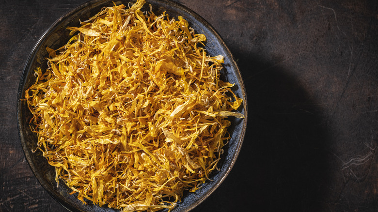 A bowl of dried lemon peel on a dark table