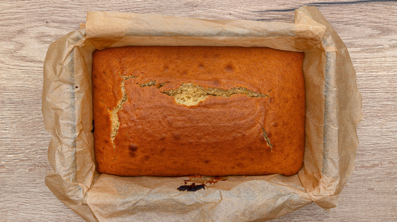 A rectangular cake sits in a pan lined with parchment paper.