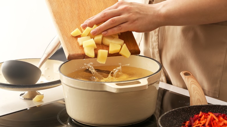 adding potatoes to simmering pot