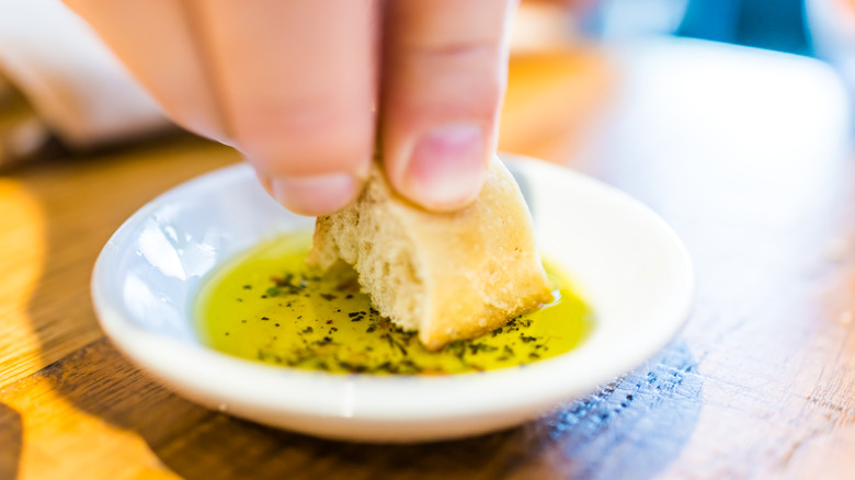 Fingers dipping bread into oil