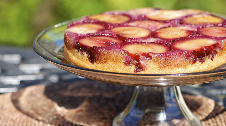 A plum upside down cake on a glass platter