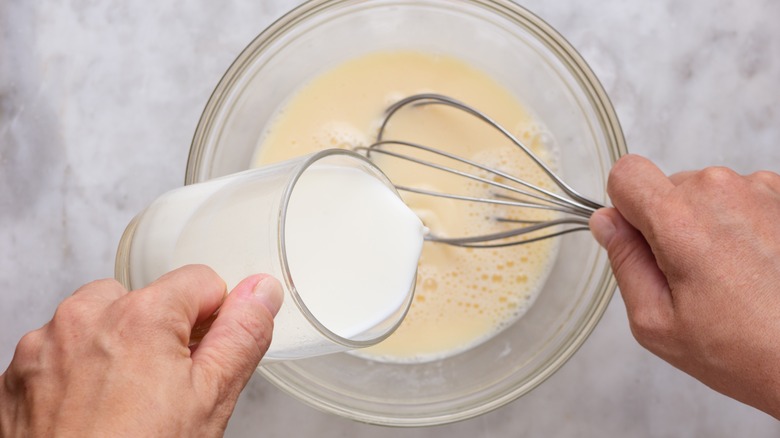 Hands pouring milk into recipe