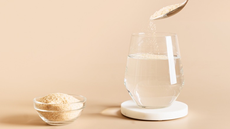 Light-colored nutritional powder being spooned into water