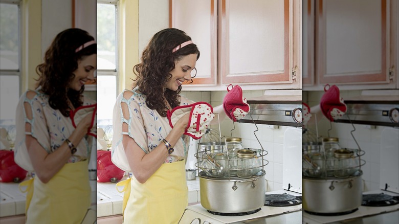 Woman sterilizing jars in a pot in the sink