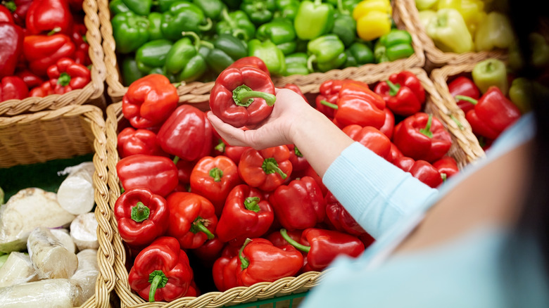 grocery shopper choosing red pepper