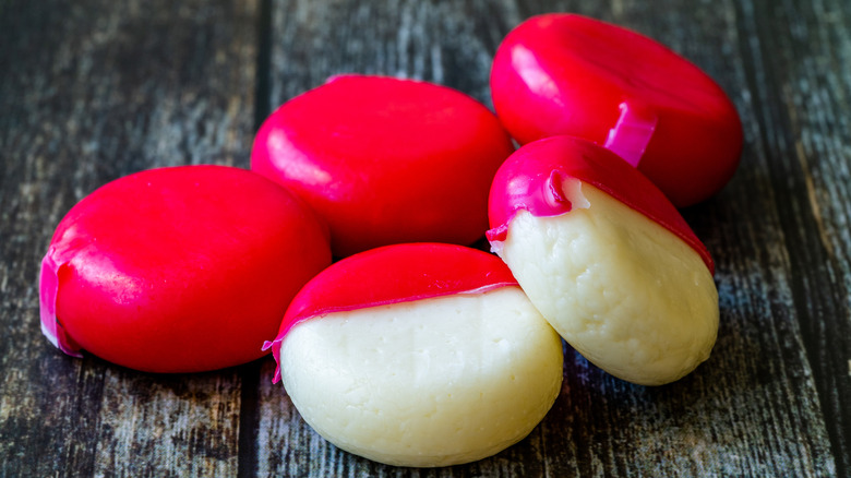 Unpeeled and peeled Babybel cheeses on table