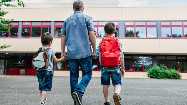 dad walking boys to school with backpacks