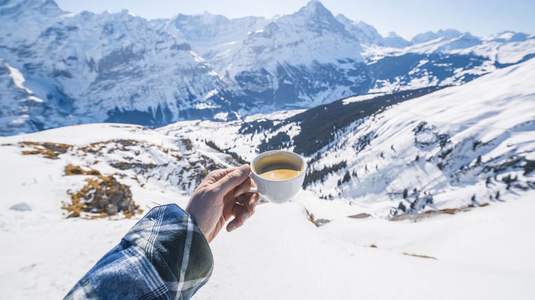 Person holding cup of coffee in the mountains in Switzerland