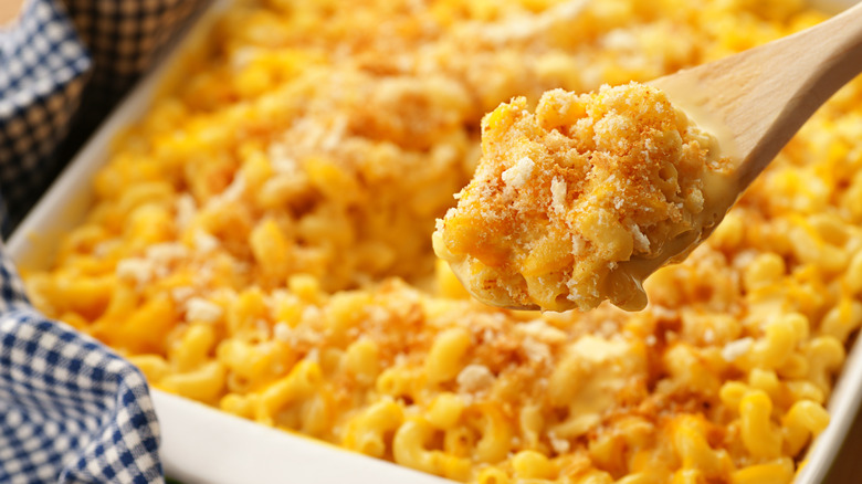 Spoonful of baked mac and cheese hovering over a casserole dish