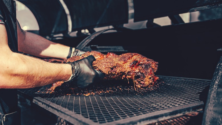 hands turning a smoked cut of meat