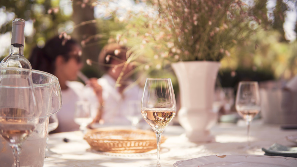 Pale wine in glasses outdoors with people in background