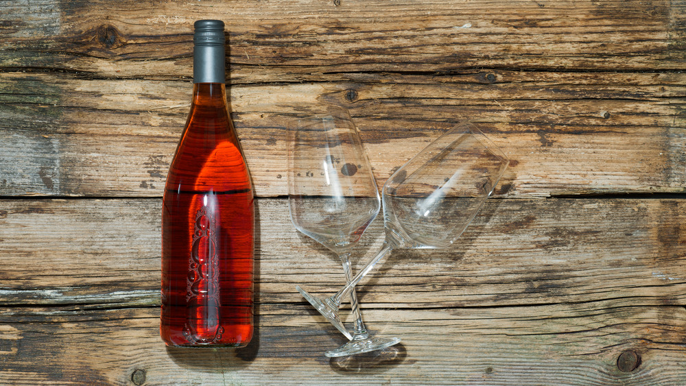 rosé wine in bottle with empty glasses on wood surface