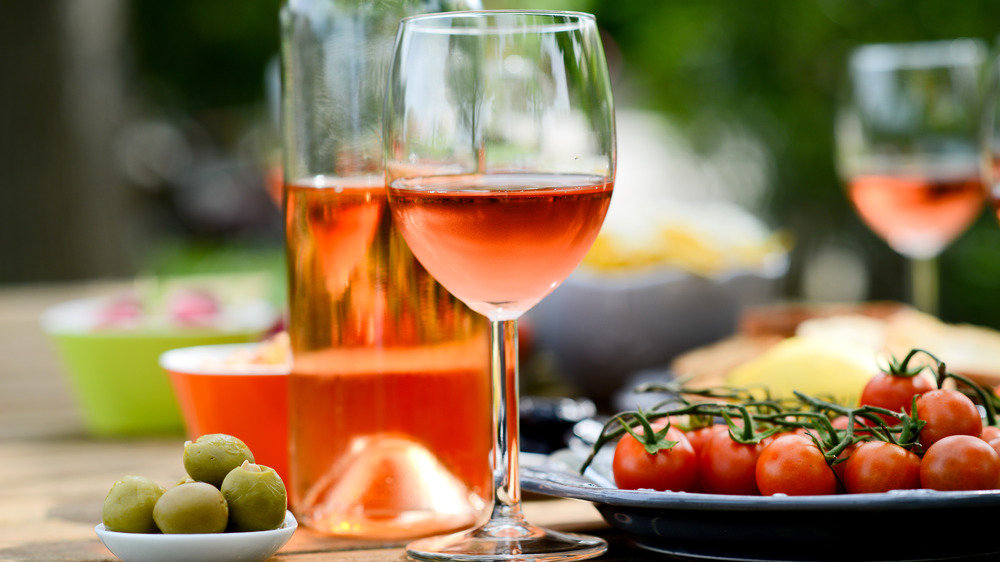 rosé wine in a bottle and glass on a table next to tomatoes