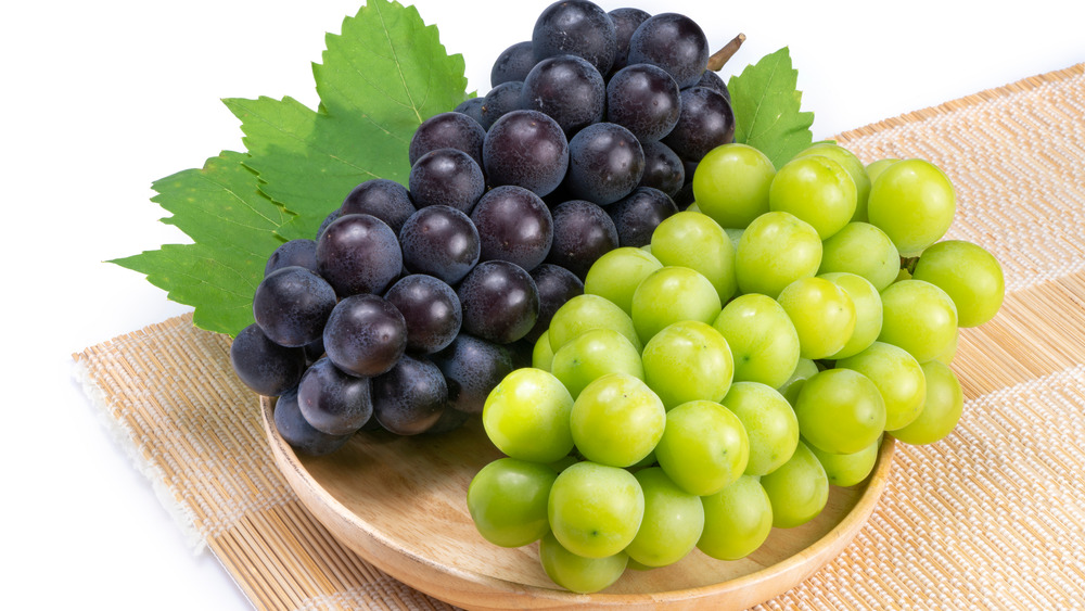 purple and green grapes on a wooden bowl