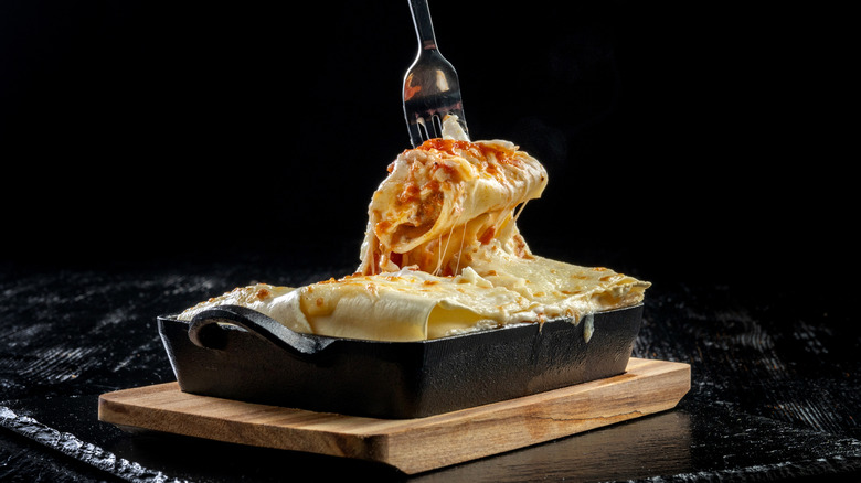 Fork in cast iron pan of lasagna