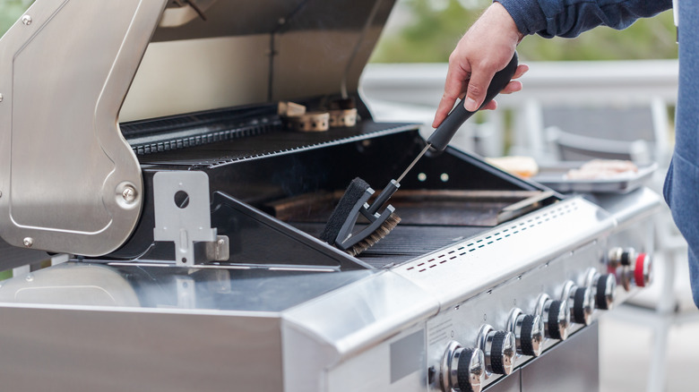 Person cleaning an outdoor grill 