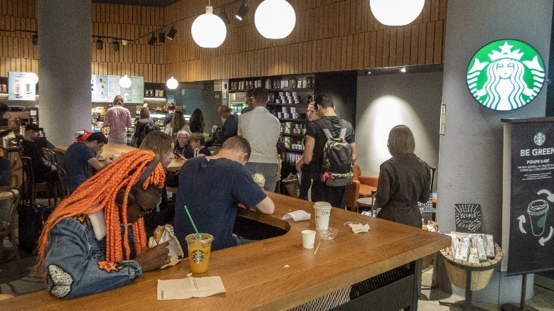 Patrons interacting near merchandise at a busy Starbucks store