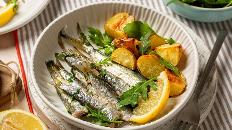 sardines, potatoes and lemon wedge on a plate