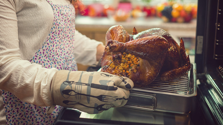 Home cook pulling a stuffed turkey out of the oven