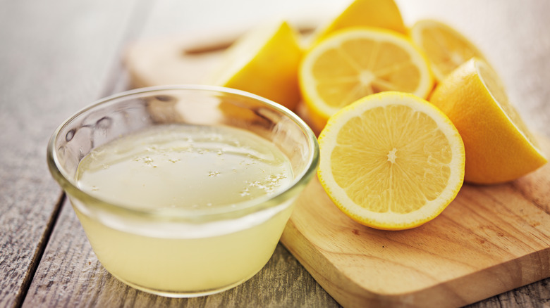 Lemon juice in bowl cut lemons chopping board