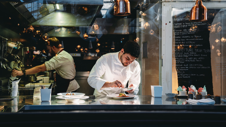 A cook plating a meal in a commercial kitchen