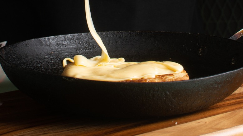 A string of melty cheese over a skillet with a partial grilled cheese
