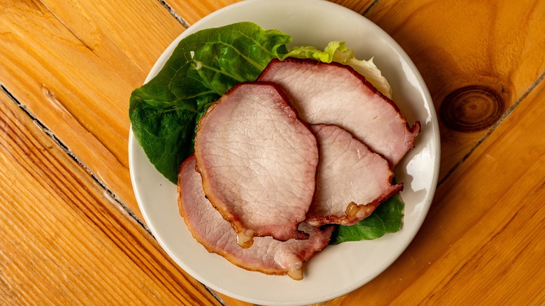 Canadian bacon on a plate with lettuce leaves