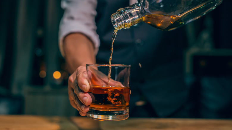 Bartender pouring whiskey into a glass