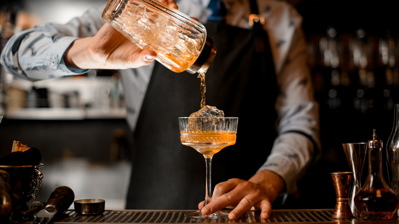 Bartender pouring a chilled cocktail from a shaker