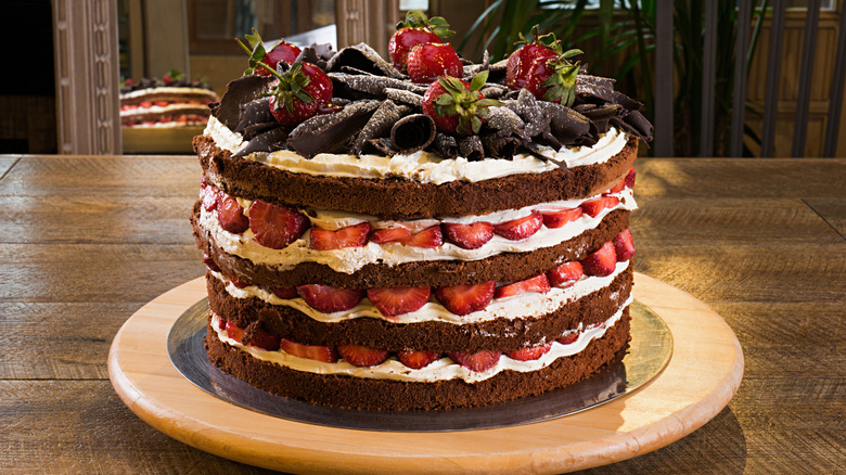 Naked layered chocolate cake with cream and strawberries