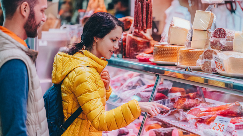 Two foodies buying organic meat from an outdoor farmers market stand