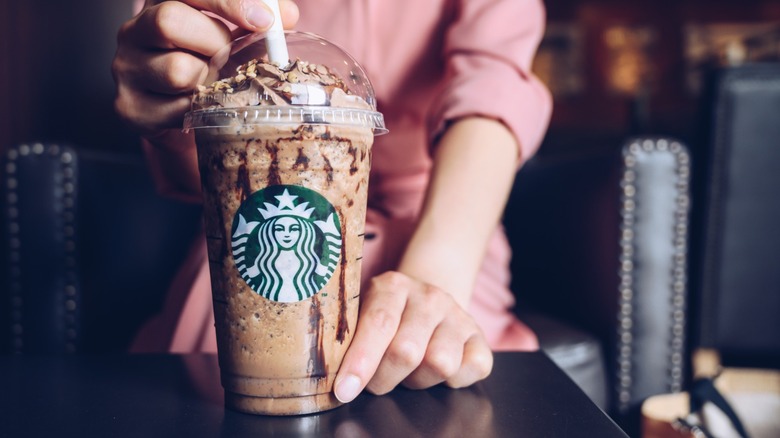 A person holding a blended Starbucks drink with whipped cream