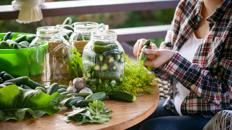 A woman prepares cucumbers for pickling at a table