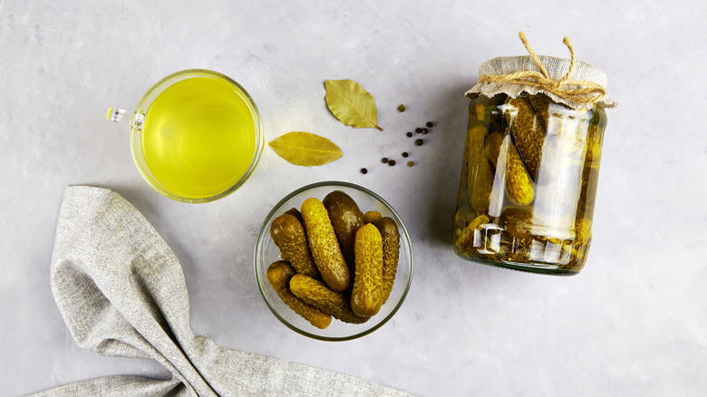 pickles in a glass bowl and jar beside a glass of pickle juice