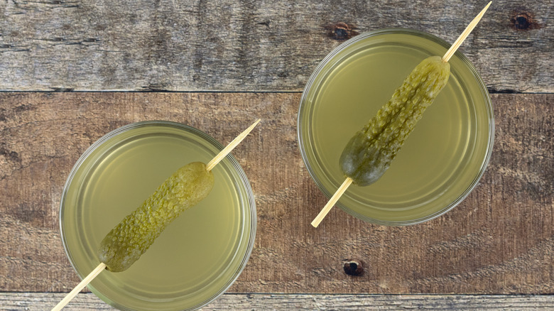 A pair of pickle juice drinks with pickle garnishes