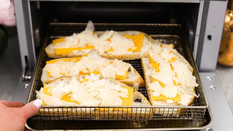 Bread pieces with cheese in air fryer basket 