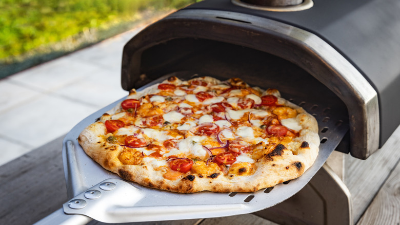 A homemade pizza is placed into a personal pizza oven