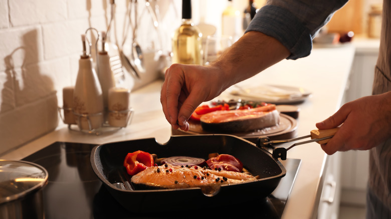 Seasoning salmon steaks in skillet 