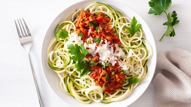 Plate of zoodles topped with red sauce and cheese