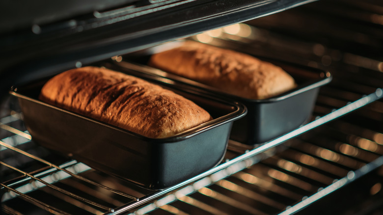 Two loaves of bread baking in the oven in metal pans