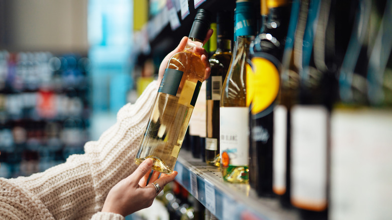 Hands holding a bottle of wine at a liquor store