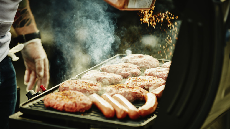 person grilling with lid open