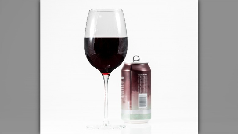 glass of red wine poured from can