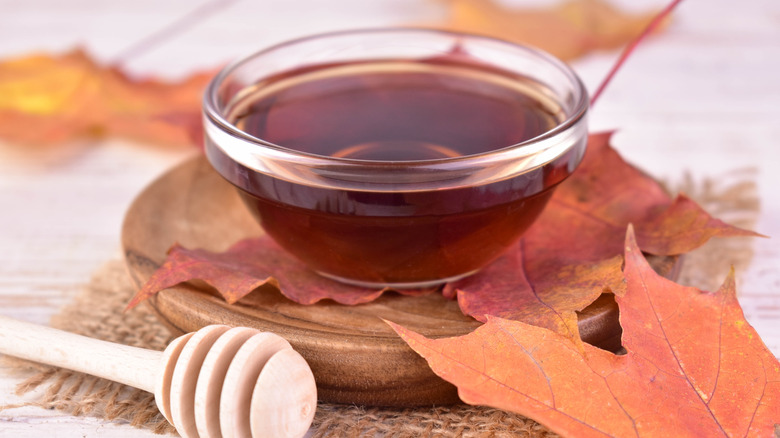 A small bowl of maple syrup beside a honeycomb wand