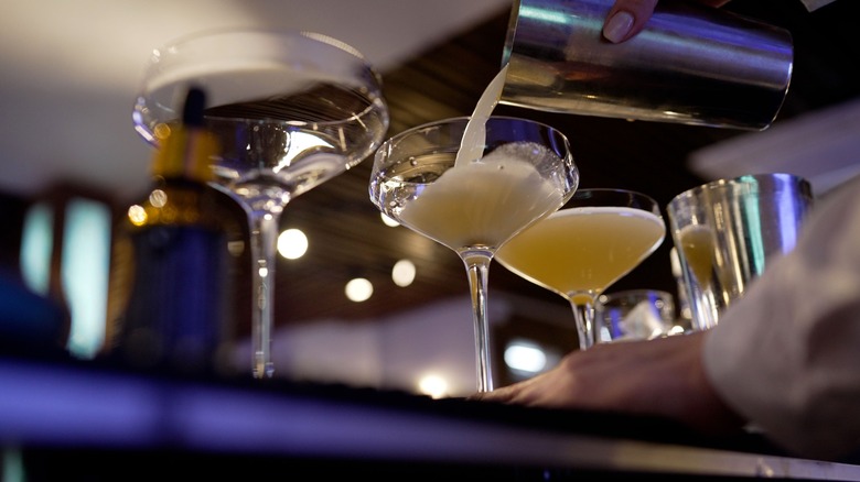 Hand pouring cocktails into glasses