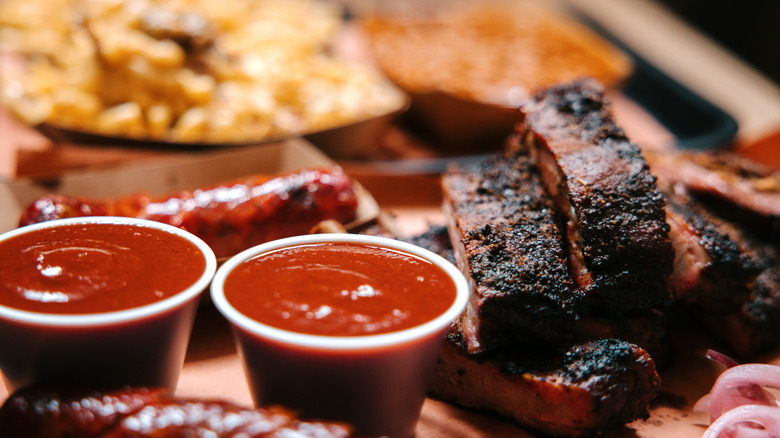 A close-up of a barbecue tray with sauce and sliced meat