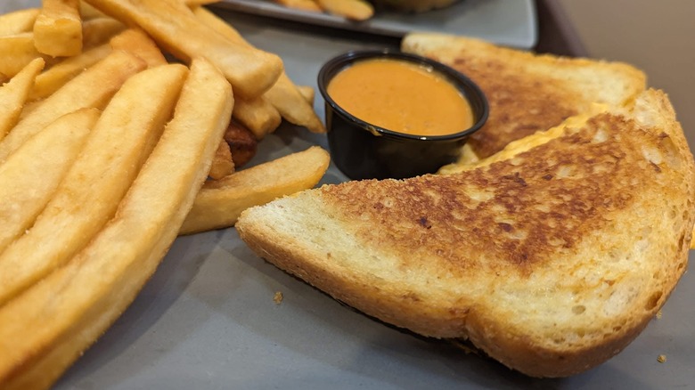 ABC Commissary Buffalo Chicken sandwich with fries and dipping sauce on plate