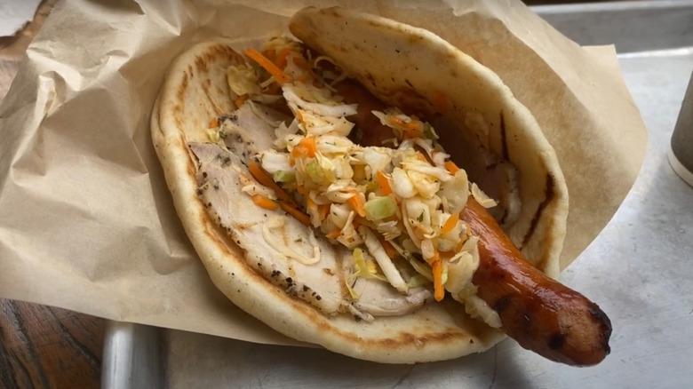 Ronto wrap of pork sausage, roasted, pork, and cole slaw on table